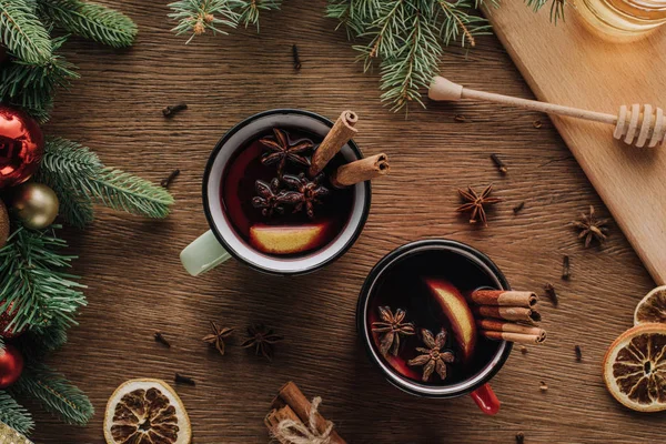 Vista superior de las copas de vino caliente con clavel y palos de canela en la mesa de madera, concepto de Navidad - foto de stock