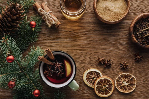 Vista superior de especiarias vinho ruminado e ramos de abeto com bugigangas em mesa de madeira, conceito de natal — Fotografia de Stock