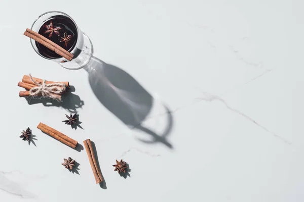 Elevated view of glass of mulled wine, carnation and cinnamon sticks on white tabletop — Stock Photo