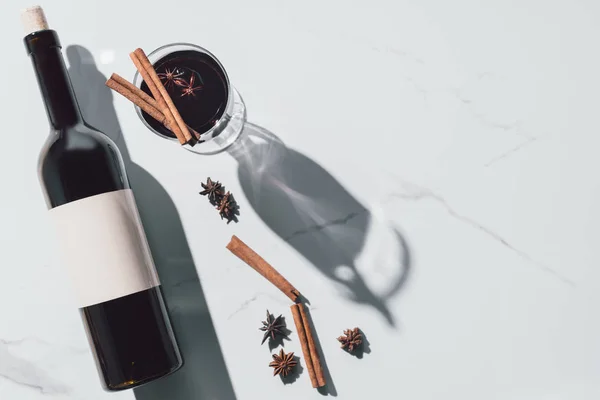 Vue du dessus du vin chaud en verre et bouteille de vin sur table blanche — Photo de stock