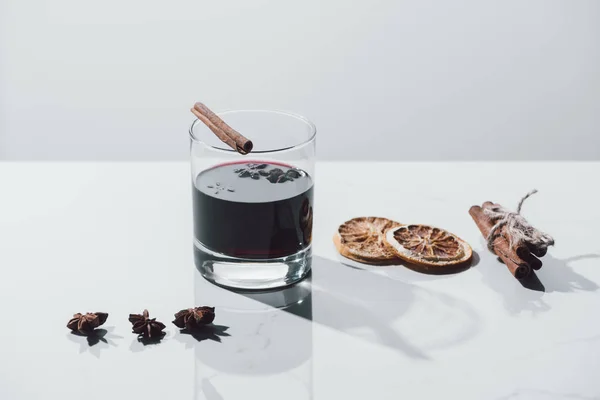 Vinho ruminado em vidro e laranjas secas em mesa branca — Fotografia de Stock