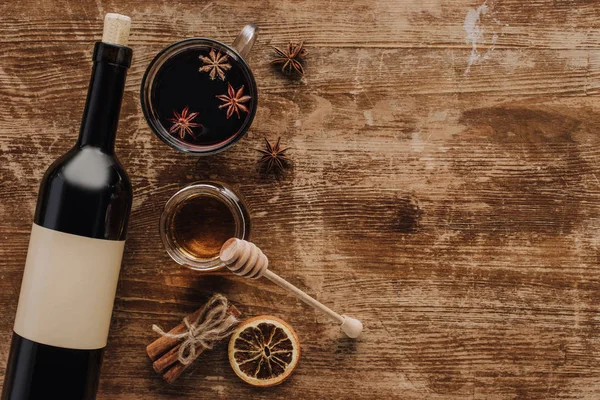 Top view of mulled wine, honey and wine bottle on wooden table — Stock Photo