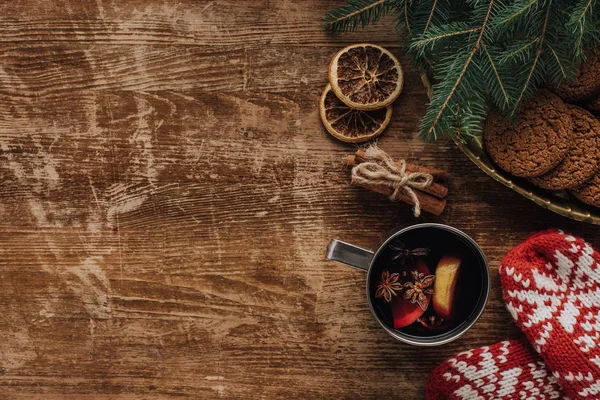 Vista elevada de vino caliente en copa, manoplas y galletas sobre mesa de madera, concepto de Navidad - foto de stock