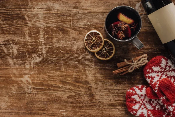 Vista superior del vino caliente en taza, mitones y botella de vino en la mesa de madera, concepto de Navidad - foto de stock