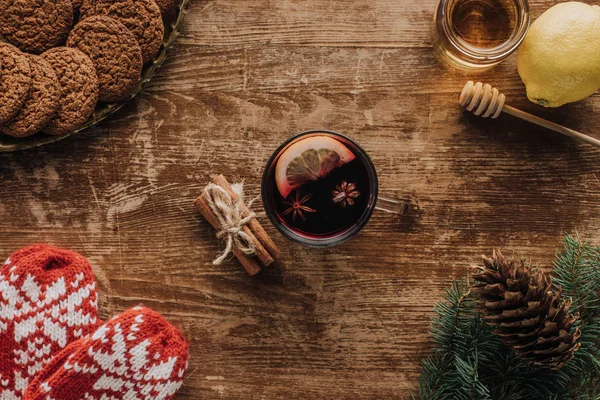 Blick von oben auf Glühwein im Becher, Fäustlinge, Tannenzweige und Honig auf Holztischplatte, Weihnachtskonzept — Stockfoto