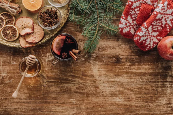 Vista superior de vino caliente en copa, ramitas de abeto de Navidad y mitones en la mesa de madera - foto de stock