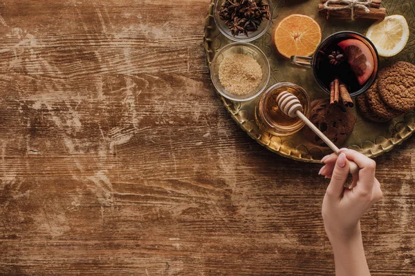 Immagine ritagliata di donna che tiene il bastone di miele a tavola di legno — Foto stock