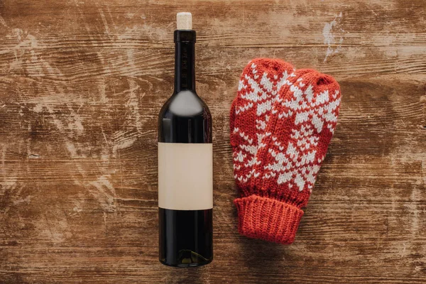 Top view of wine bottle and winter mittens on wooden tabletop, christmas concept — Stock Photo