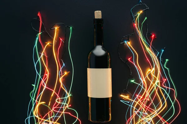 Vista dall'alto di bottiglia di vino e ghirlanda luci con lunga esposizione isolata sul nero, concetto di Natale — Foto stock
