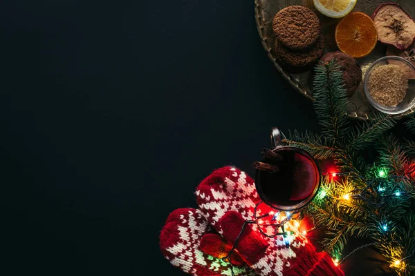 Top view of cup of mulled wine, garland, mittens and cookies isolated on black, christmas concept — Stock Photo