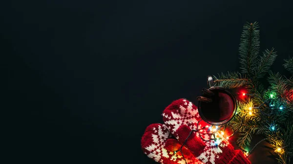 Vista elevada de la copa de vino caliente, guirnalda y mitones aislados en negro, concepto de Navidad - foto de stock