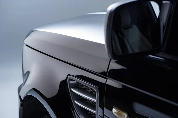 Close up vista de novo carro preto brilhante no fundo escuro — Fotografia de Stock