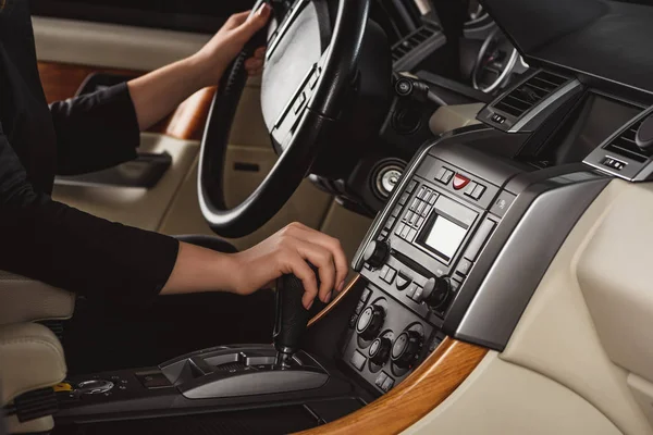 Cropped shot of woman changing gear while driving new car — Stock Photo