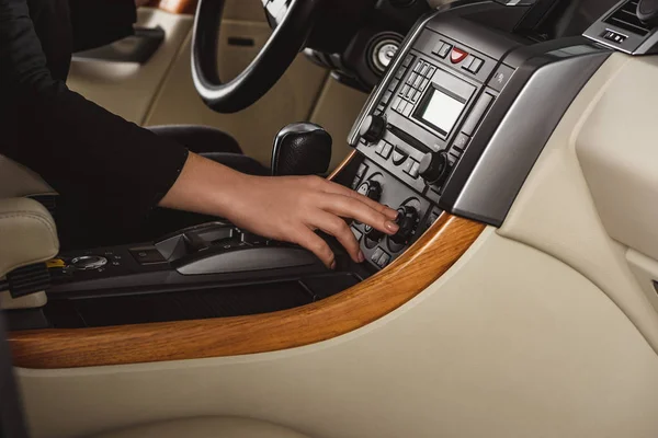 Cropped shot of woman turning on climate control driving new car — Stock Photo