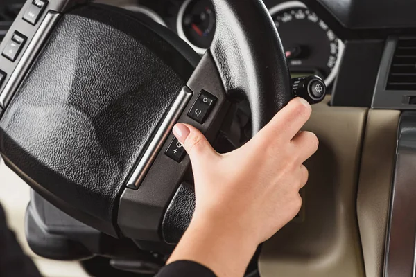 Cropped shot of woman turning on speed limitation while driving car alone — Stock Photo