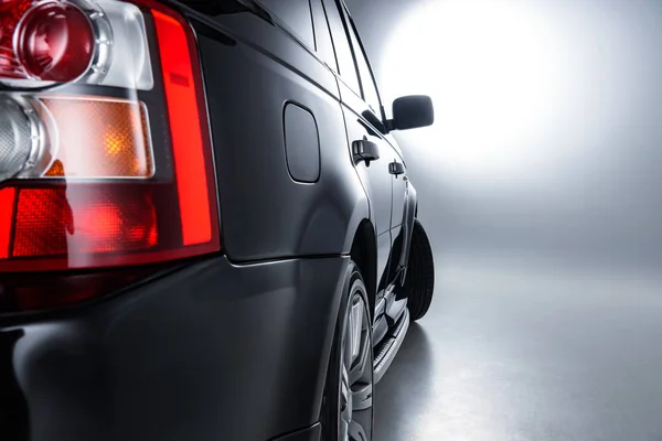 Close up view of rear headlight rear of luxury black car on grey backdrop — Stock Photo