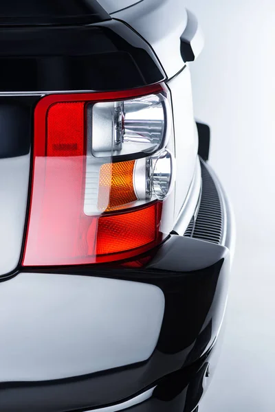 Close up view of rear headlight of luxury black car on grey backdrop — Stock Photo