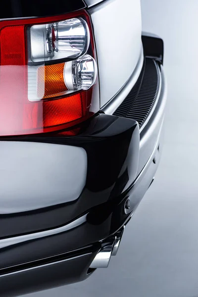 Close up view of rear headlight of luxury black car on grey backdrop — Stock Photo