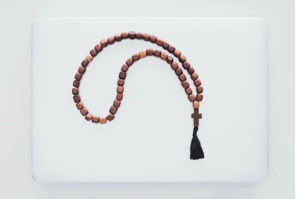 Top view of beads lying on closed laptop on white surface — Stock Photo