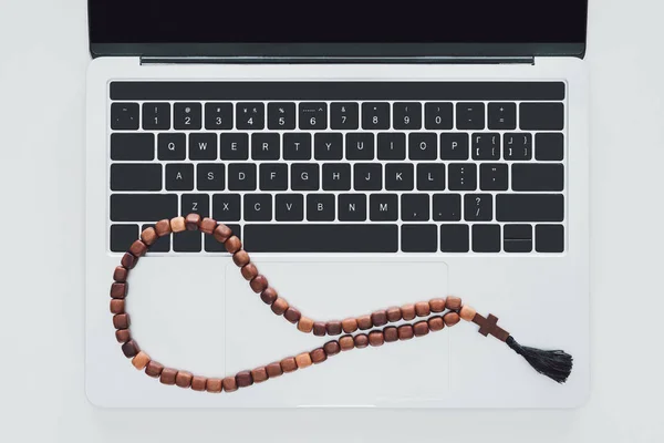 Top view of beads lying on laptop on white surface — Stock Photo