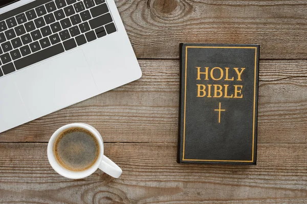 Top view of holy bible with laptop and coffee on wooden table — Stock Photo