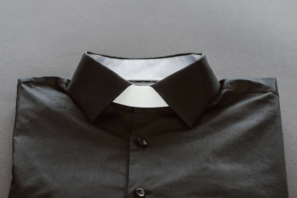 Primer plano de camisa clerical con cuello blanco sobre superficie gris - foto de stock