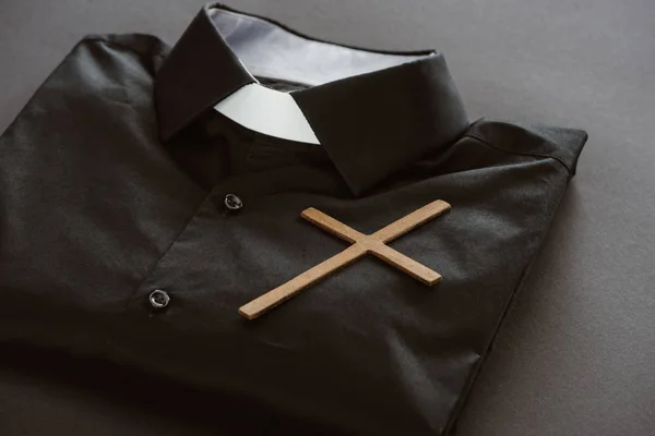 Close-up shot of clerical shirt with cross on grey surface — Stock Photo