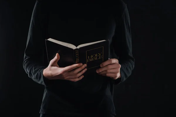 Plan recadré de prêtre lecture sainte bible isolé sur noir — Photo de stock