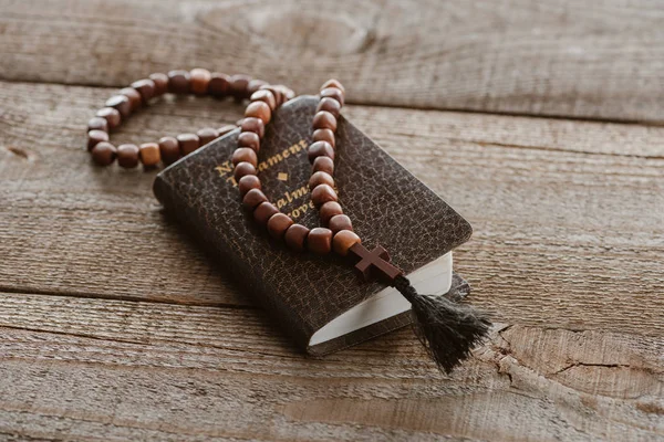 Close-up shot of new testament book with beads on wooden table — Stock Photo