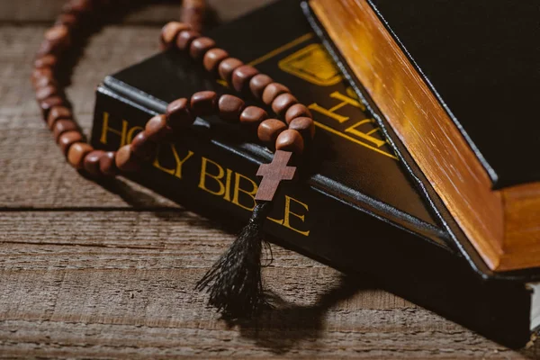 Close-up shot of holy bibles with beads on wooden table — Stock Photo