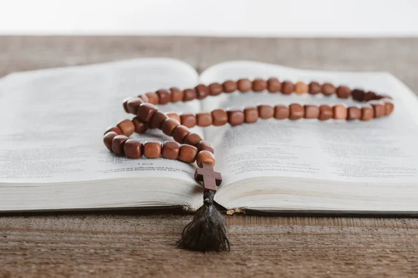 Primer plano de la biblia santa con cuentas en la mesa de madera - foto de stock