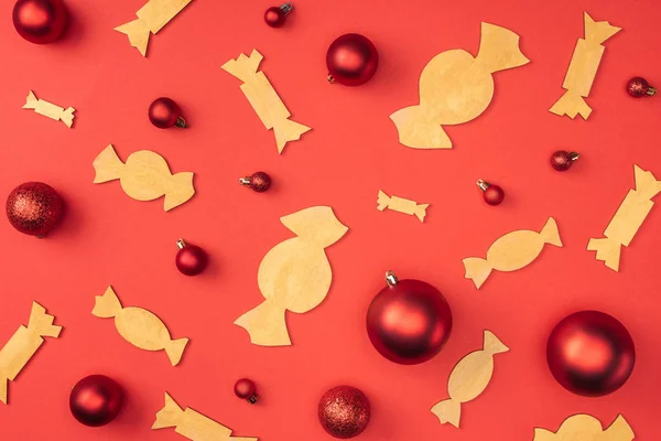 Acostado plano con juguetes de Navidad rojos y caramelos de madera decorativos aislados en rojo - foto de stock