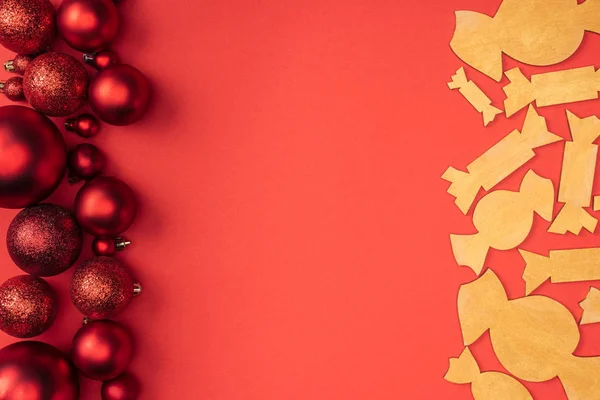 Acostado plano con juguetes de Navidad rojos y caramelos de madera decorativos aislados en rojo - foto de stock