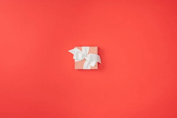 Vue du dessus du cadeau de Noël enveloppé avec ruban blanc isolé sur rouge — Photo de stock