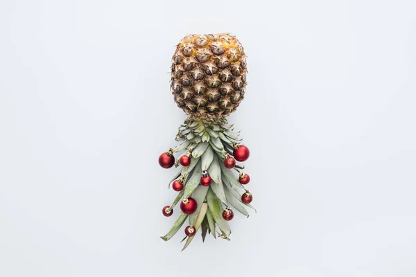 Vue de dessus des boules de Noël rouges sur l'ananas frais isolé sur blanc — Photo de stock