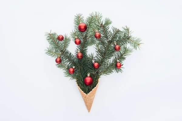 Вид зверху на червоні різдвяні іграшки на гілках соснового дерева в конусі морозива ізольовані на білому — стокове фото