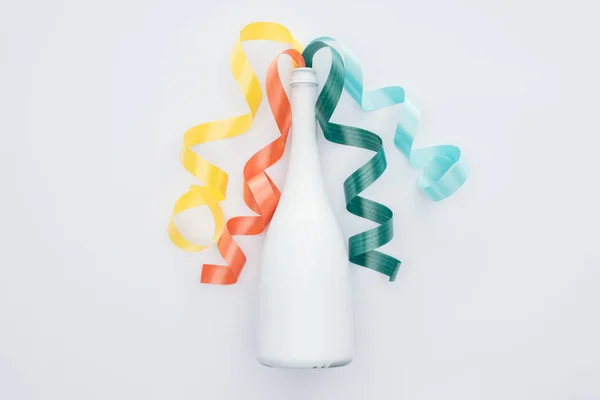 Вид сверху на красочные ленты и белую бутылку, изолированную на белом — стоковое фото