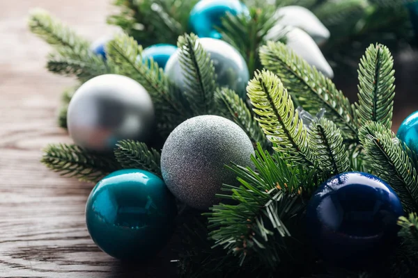Vista de cerca de la corona de pino con juguetes de navidad azules y plateados sobre fondo de madera - foto de stock