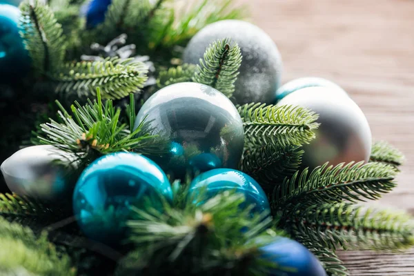 Vista de cerca de la corona de pino con juguetes de navidad azules y plateados sobre fondo de madera - foto de stock