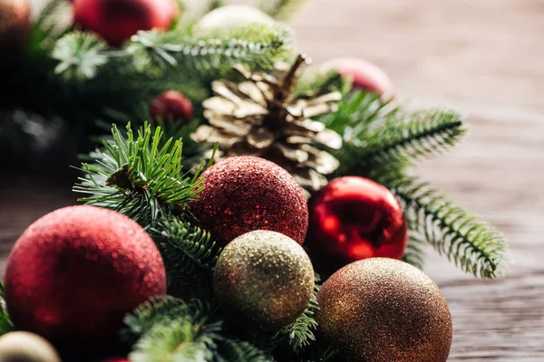 Vista de cerca de la corona de pino con bolas de Navidad rojas y doradas sobre fondo de madera - foto de stock