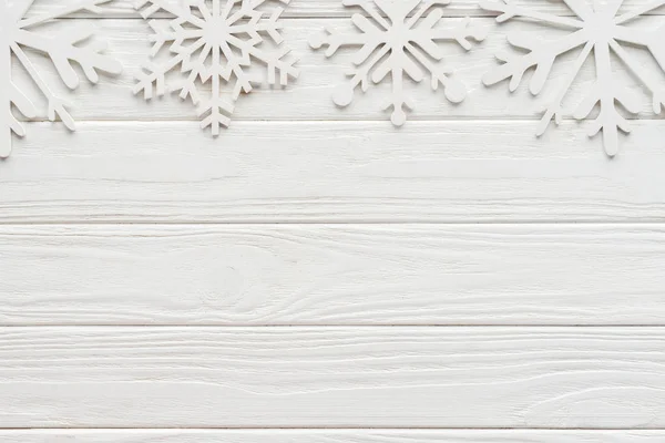 Deitado plano com flocos de neve decorativos em mesa de madeira branca — Fotografia de Stock