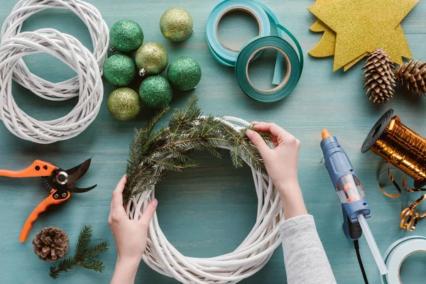 Teilansicht einer Frau beim Basteln eines handgefertigten Adventskranzes auf blauer Holzoberfläche — Stock Photo