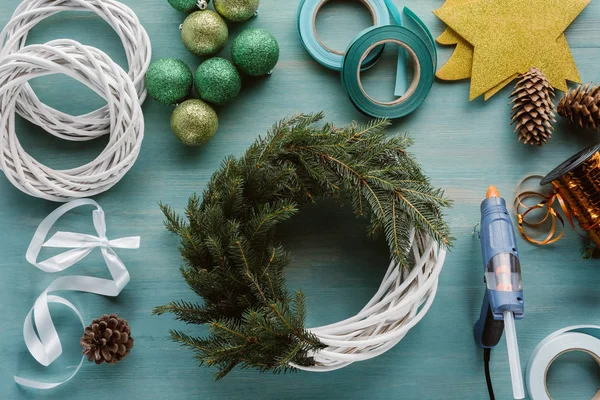 Flat lay with arranged pine tree branches and decorations for handmade christmas wreath on blue wooden tabletop — Stock Photo