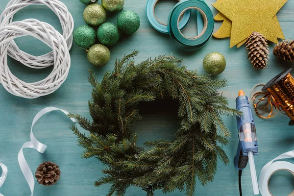 Blick von oben auf arrangiertes Weihnachtsspielzeug und Dekorationen für handgefertigten Adventskranz auf blauer Holztischplatte — Stockfoto