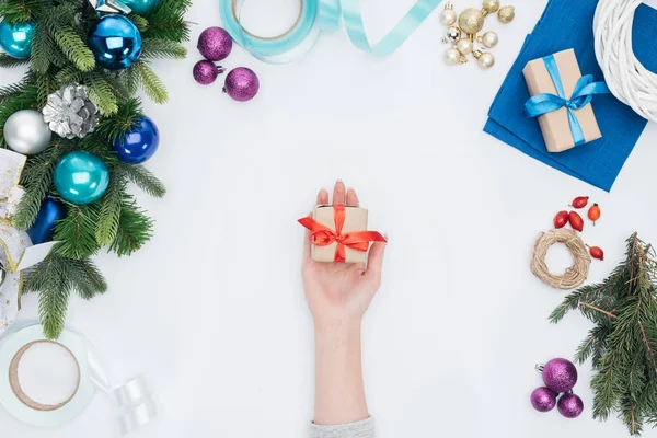 Partial view of woman holding wrapped christmas gift with red ribbon isolated on white — Stock Photo