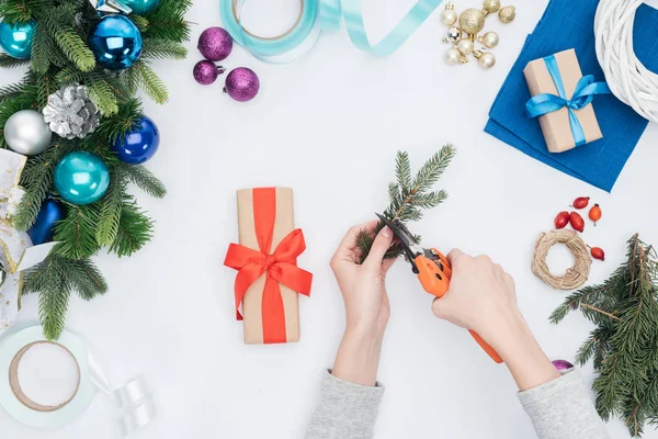 Vista parcial de la mujer decorando navidad presente con rama de pino aislado en blanco - foto de stock