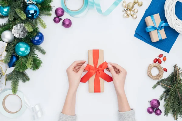 Tiro recortado de mujer sosteniendo regalo de Navidad envuelto con cinta roja aislada en blanco - foto de stock