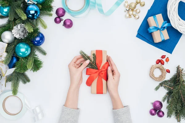 Vista parcial de la mujer decorando navidad presente con rama de pino aislado en blanco - foto de stock