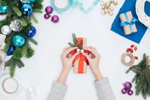 Частковий вид жінки, що прикрашає обгорнуті подарунки різдвяними кульками ізольовані на білому — стокове фото