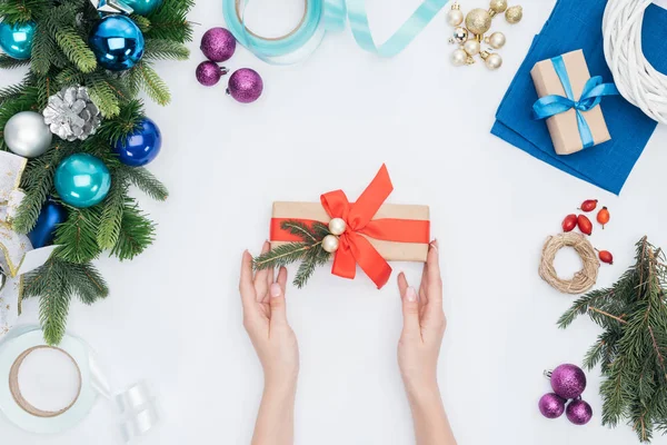 Tiro recortado de mujer sosteniendo regalo de Navidad envuelto con cinta roja aislada en blanco - foto de stock